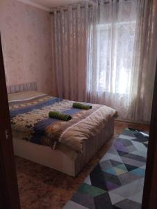 a bedroom with a bed and a window with curtains at Karakol apartment in Karakol