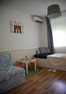 a bedroom with a bed and a chair and a table at Helikon 32 Apartman Keszthely in Keszthely