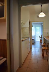 a kitchen with white cabinets and a tile floor at Helikon 32 Apartman Keszthely in Keszthely