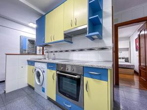 a kitchen with blue and yellow cabinets and a dishwasher at Apartamento coqueto gran Bilbao in Basauri