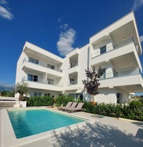 a large white apartment building with a swimming pool at VILLA CALA, Hotel Rooms&Apartments in Novalja