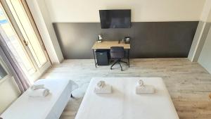 two beds in a room with a desk and a television at Bed & Bike Feltre in Feltre