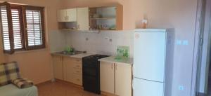 a kitchen with a white refrigerator and a sink at Apartmani Kerum in Jelsa