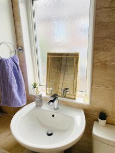 a bathroom with a sink and a mirror and a toilet at Entire 4 bedroom House - EV POINT & FREE PARKING in Liverpool