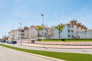 een straat met gebouwen en palmbomen voor een weg bij Playa del Pinet Apartment in La Marina