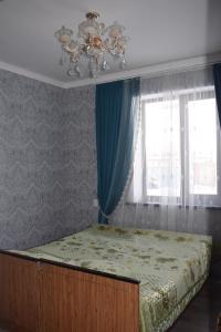 een slaapkamer met een bed met een kroonluchter en een raam bij Kyzart Guesthouse in Bagysh