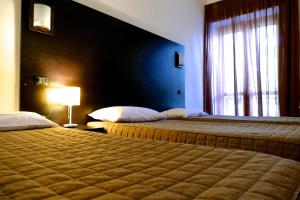 Hotel Colucci في Nusco: غرفة فندقية بسريرين ونافذة