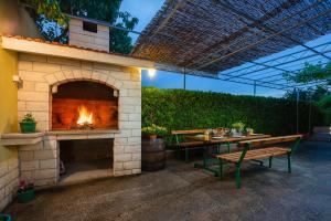 een patio met een open haard, een tafel en een bank bij Holiday Residence Maja in Katuni