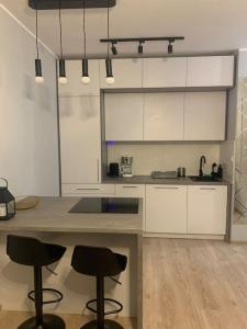 una cocina con armarios blancos y taburetes negros en Comfort18, en Bydgoszcz