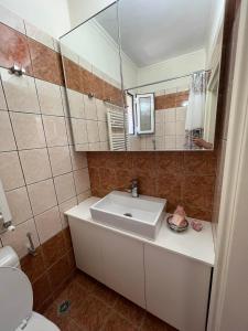 a bathroom with a sink and a toilet and a mirror at Cozy House in Lagonisi in Áyios Nikólaos