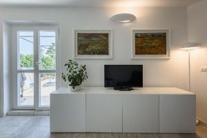 - un salon blanc avec une télévision sur une armoire blanche dans l'établissement Your Loft in Florence, à Florence