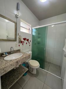 a bathroom with a toilet and a sink and a shower at Recanto Armação Pousada in Penha