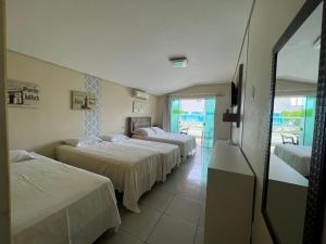 a hotel room with three beds and a balcony at Recanto Armação Pousada in Penha
