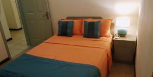 1 dormitorio con 1 cama con almohadas de color naranja y azul en Paradya Beach Apartments, en Flic en Flac