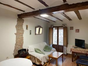 sala de estar con sofá blanco y TV en Casa Rural Aras Apartamentos Turísticos, en Aras de Olmos