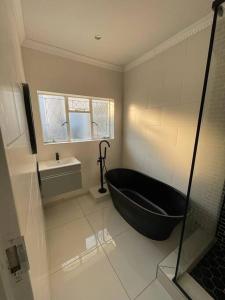 ein Badezimmer mit einer schwarzen Badewanne und einem Waschbecken in der Unterkunft 15 St Aidans in Grahamstown