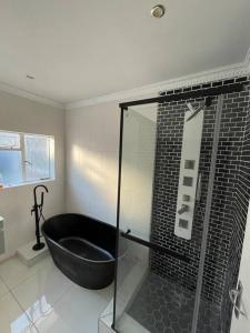 ein Bad mit einer schwarzen Badewanne und einer Dusche in der Unterkunft 15 St Aidans in Grahamstown