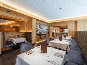 un restaurante con mesas y sillas blancas y una pantalla en Hotel Alpina, en Ried im Zillertal