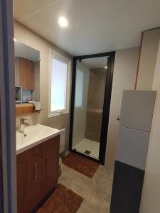 a bathroom with a sink and a shower and a refrigerator at Mobil Home neuf Hyères in Hyères