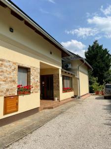 Una casa con dos ventanas con flores rojas. en See Haus - Podmaniczky Szállás, Bor, Balaton, en Balatonföldvár