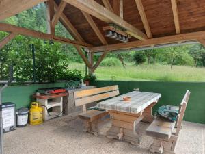 a picnic table and bench under a wooden pavilion at Apartmaji Katrč in Soča