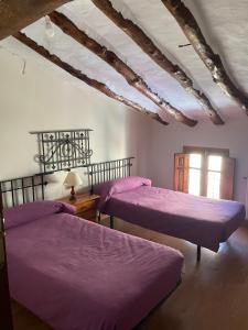 - 2 lits dans une chambre avec des draps violets dans l'établissement Casa Rural Aras Apartamentos Turísticos, à Aras de Olmos