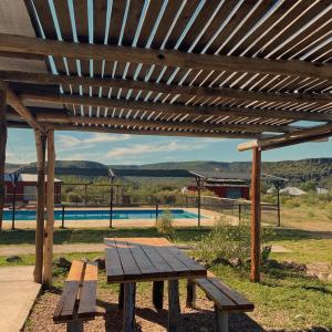 una mesa de picnic bajo una pérgola de madera junto a una piscina en Cabañas Vistas Andinas en Valle Grande