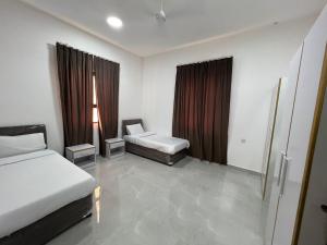 Cette chambre comprend 2 lits et une fenêtre. dans l'établissement Red-3 - New Salalah, à Salalah