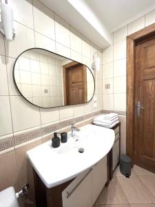 ein Bad mit einem Waschbecken und einem Spiegel in der Unterkunft Żeromskiego Residence in Słupsk