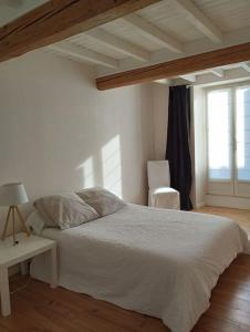 - une chambre avec un lit blanc et une fenêtre dans l'établissement gite au village, à Mourvilles-Hautes