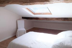 ein Schlafzimmer mit einem weißen Bett und einem Dachfenster in der Unterkunft gite au village in Mourvilles-Hautes