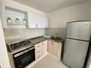 a kitchen with a white refrigerator and a stove at Apartamento Edificio Mar Adentro 15 ICDI in Cartagena de Indias