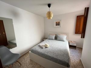 um pequeno quarto com uma cama e uma cadeira em Apartamento OLIVA PLAYA - PAU PI em Oliva