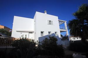 a white house with a palm tree in front of it at Villa Can Bella, 350m zum Strand in Cala Galdana