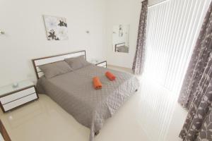 una camera da letto con un letto con due cuscini arancioni sopra di Waterside Apartments a Marsalforn