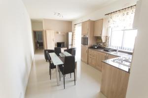 a kitchen with a table and black chairs in a room at Waterside Apartments in Marsalforn