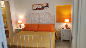 1 dormitorio con 1 cama con almohadas de color naranja y 2 lámparas en Villini di Sant'Andreas, en Monopoli