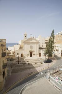 a large white building with stairs in a city at Waterside Apartments in Marsalforn