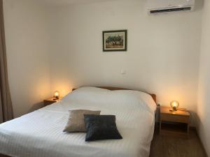een slaapkamer met een wit bed en 2 nachtkastjes bij Apartments Kankul in Krk