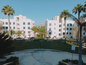 a pool with palm trees and buildings in the background at Residencial la Bahía in Santa Pola