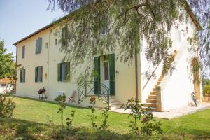 a white house with a tree in front of it at Agriturismo Morani in Santa Severa