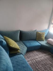 un divano blu con cuscini gialli in soggiorno di Joli appartement ad Agadir