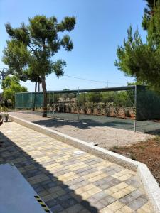 una pista de tenis con un árbol y una valla en B&B Villa VITTORIO en Nardò