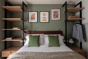 a bedroom with a bed with green pillows and shelves at TOC Hotel Las Ramblas in Barcelona