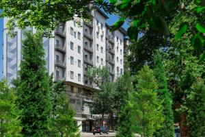 un grand bâtiment blanc avec des arbres devant lui dans l'établissement apartment in the center Rakat-11, à Tachkent
