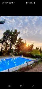 una gran piscina azul con puesta de sol en el fondo en nikol villa elani, en Siviri