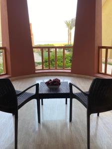 stół z dwoma krzesłami i miską owoców na nim w obiekcie Azzurra Sahl hasheesh w mieście Hurghada