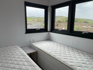 Modern villa - in Golden Circle - Gullfoss Geysir Þingvöllur - Freyjustíg 13, 805 Selfoss في Búrfell: غرفة بها نافذتين وسرير