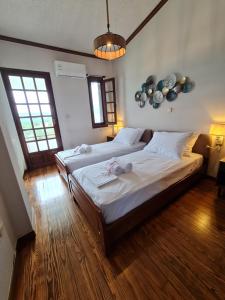 a bedroom with two beds with white sheets and wooden floors at Villa ChrysPa Attica in Dhílesi