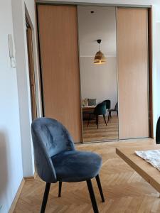 a blue chair in a living room with a table at Apartament Baltica Nawigator in Gdynia
